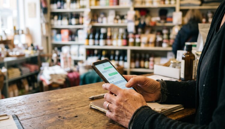 Mãos de lojista digitando no celular sobre o balcão